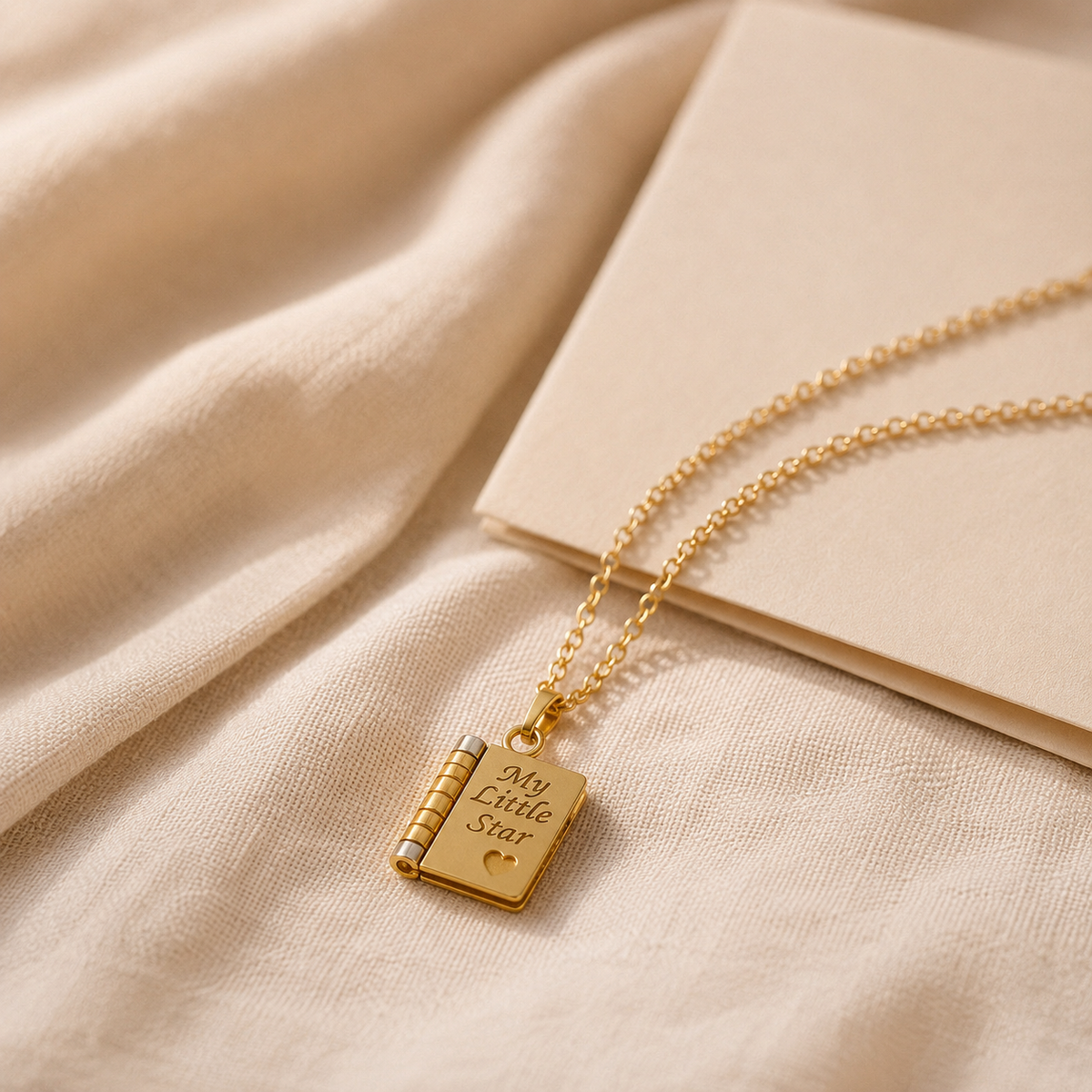 Gold engraved pendant necklace on cream linen beside a card